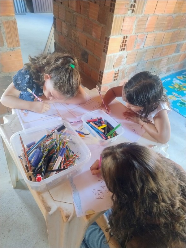 Crianças desenhando e pintando à mesa com lápis coloridos