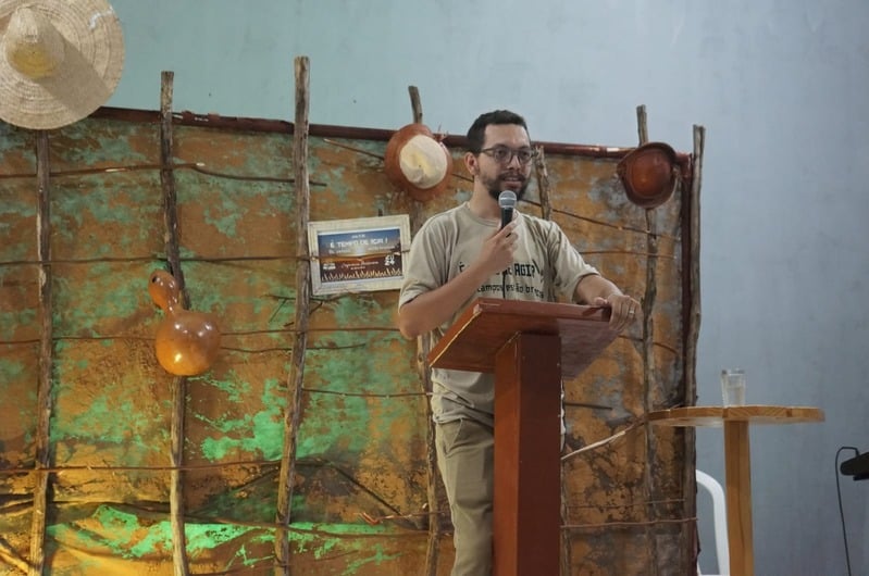Luan pregando ao púlpito durante o culto, com decoração sertaneja ao fundo