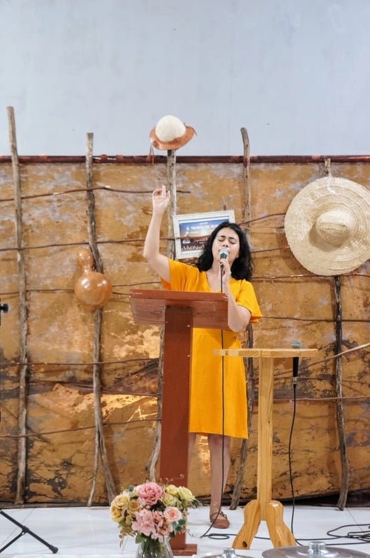 Débora ministrando o louvor ao púlpito, de mãos erguidas