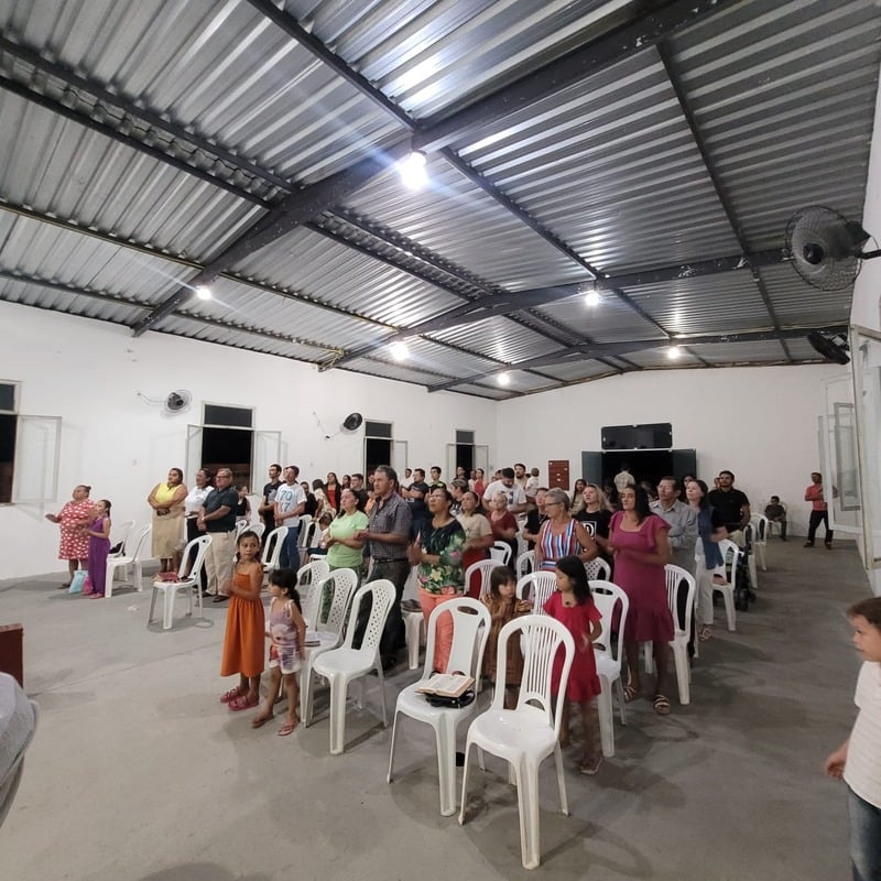Congregação em pé, em adoração, no galpão da igreja
