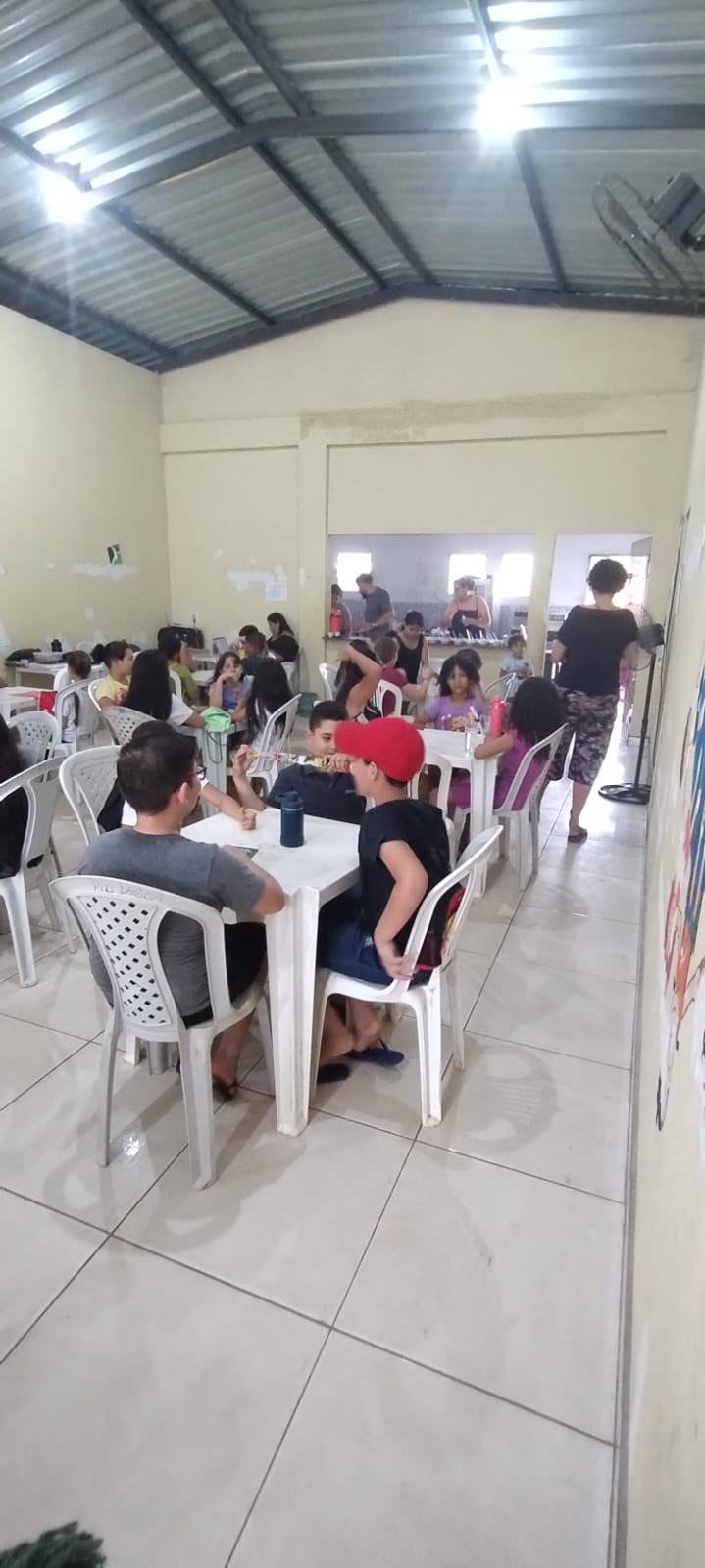 Crianças e famílias reunidas à mesa no refeitório da igreja