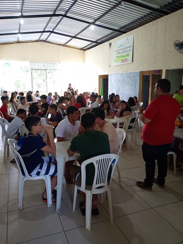 Crianças e adolescentes reunidos às mesas para o lanche no salão