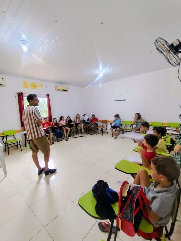 Educador em pé ensinando crianças sentadas nas carteiras